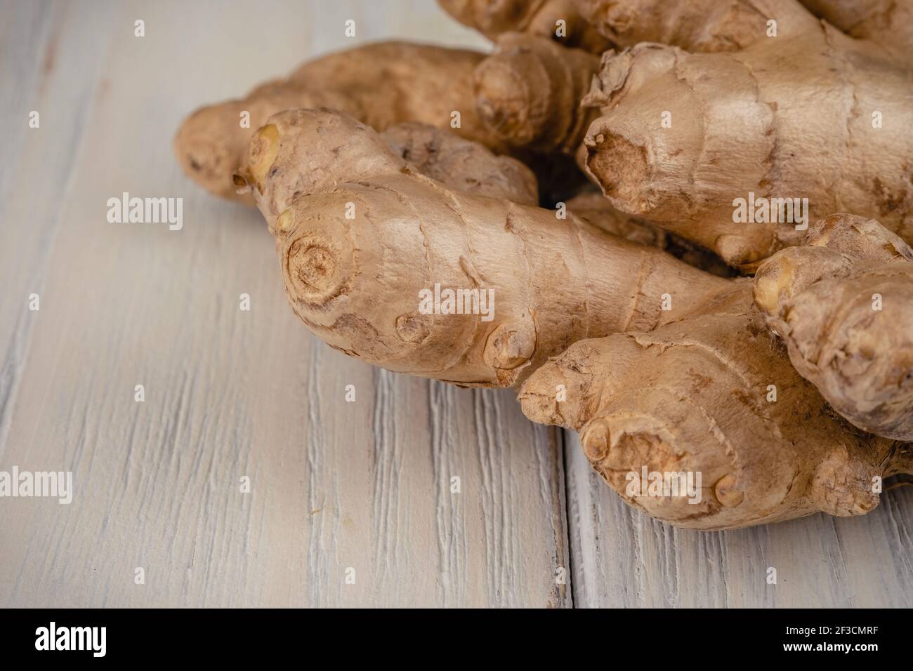 Zenzero fresco, leggero e sano su sfondo bianco di legno Foto Stock