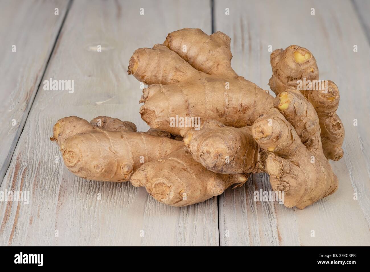 Zenzero fresco, leggero e sano su sfondo bianco di legno Foto Stock