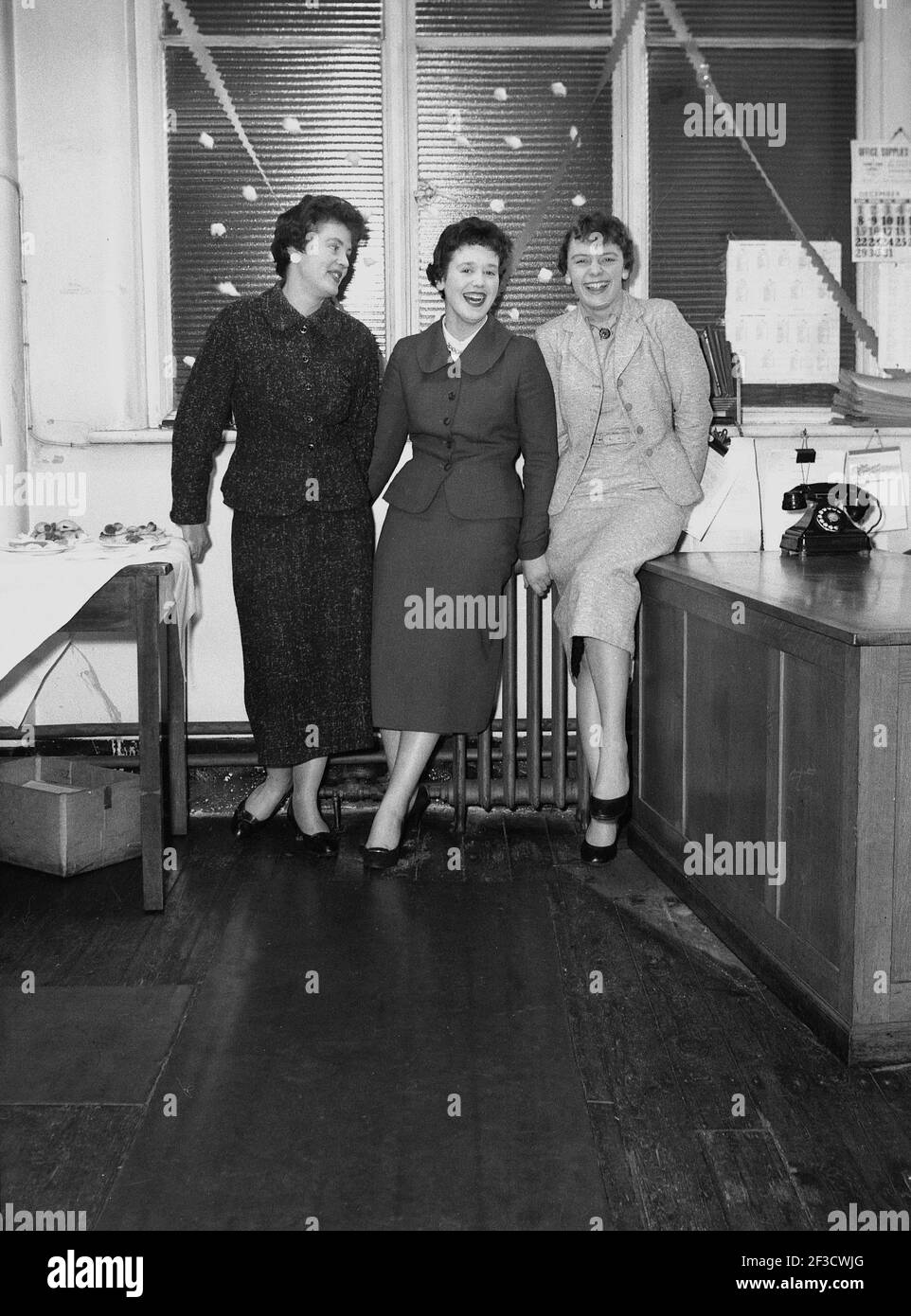 Anni '50, storico, tre giovani Signore del dyping pool in piedi insieme per la loro immagine, avendo una risata, alla Hepworths azienda di produzione di abbigliamento, Clay Pit Lane, Leeds, Inghilterra, Regno Unito, indossando gli abiti eleganti e femminili dell'epoca. Foto Stock