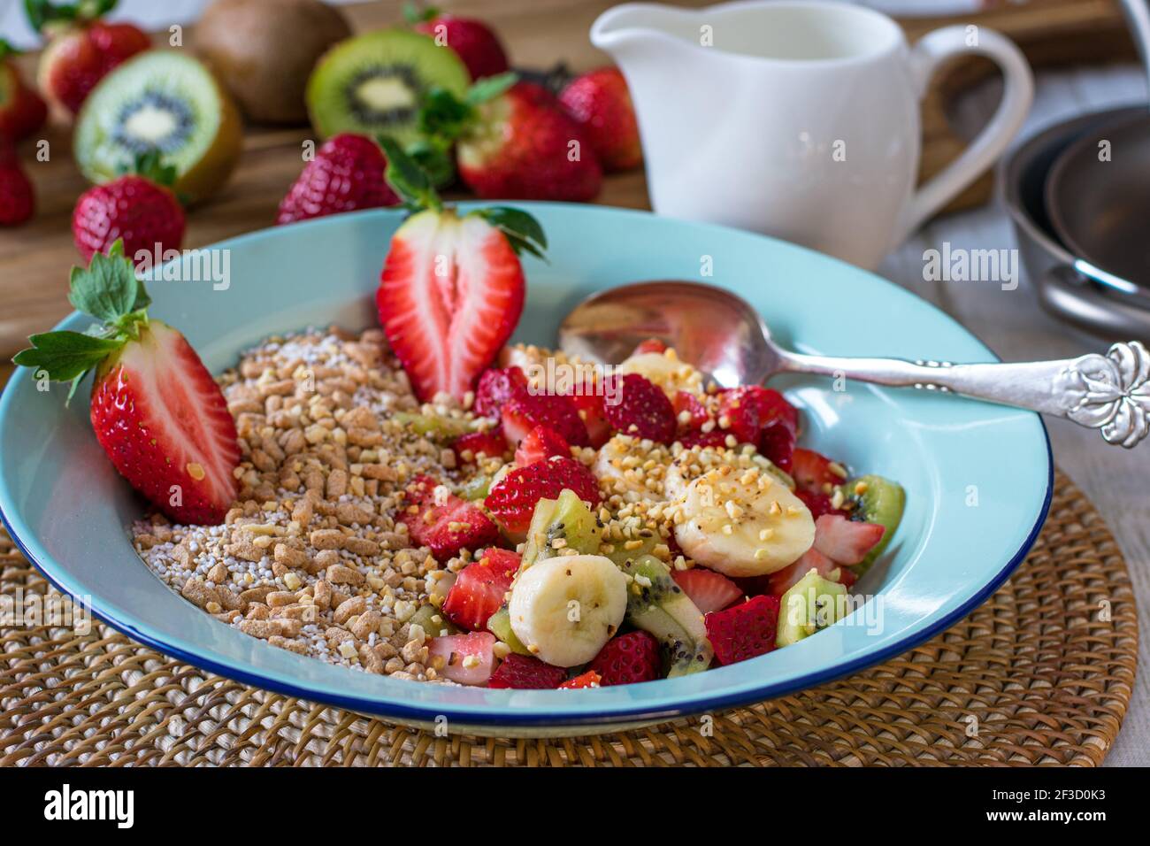 Muesli con frutta fresca e noci tostate in una ciotola su tavolo da cucina Foto Stock