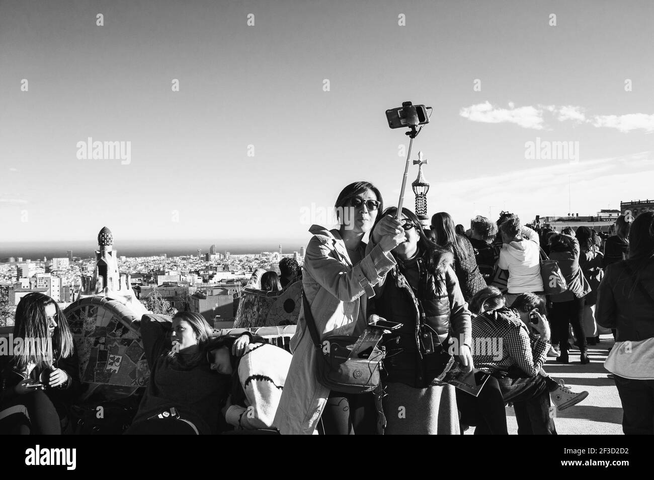 BARCELLONA, CATALOGNA, SPAGNA - 11 MARZO 2018: Turisti nel famoso parco Guell. Due giovani donne asiatiche fanno selfie con il paesaggio urbano di Barcellona. Bianco nero Foto Stock