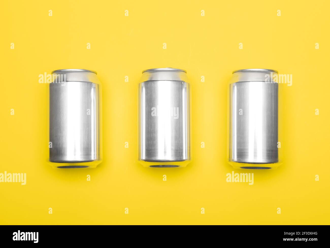 Tre lattine da 330 ml di bibite gassate in alluminio sfondo giallo Foto Stock