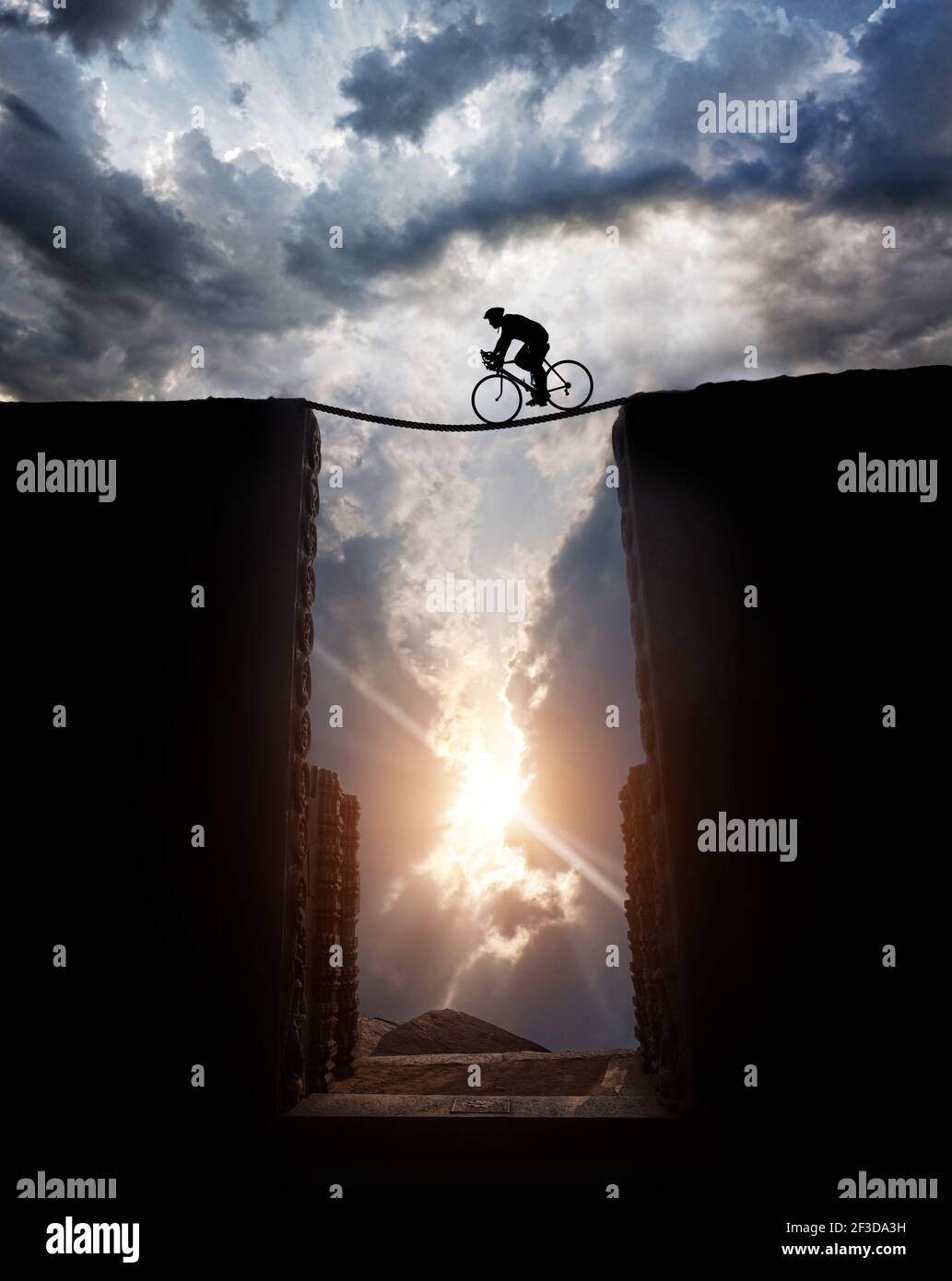 Silhouette di un uomo in bicicletta Ciclismo sopra l'abisso al tramonto cielo nuvoloso sfondo Foto Stock