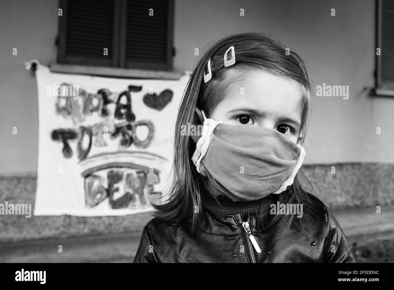 Bambina che indossa una maschera protettiva in piedi di fronte alla scuola chiusa o a casa durante l'epidemia di coronavirus - sfondo offuscato con la speranza Foto Stock