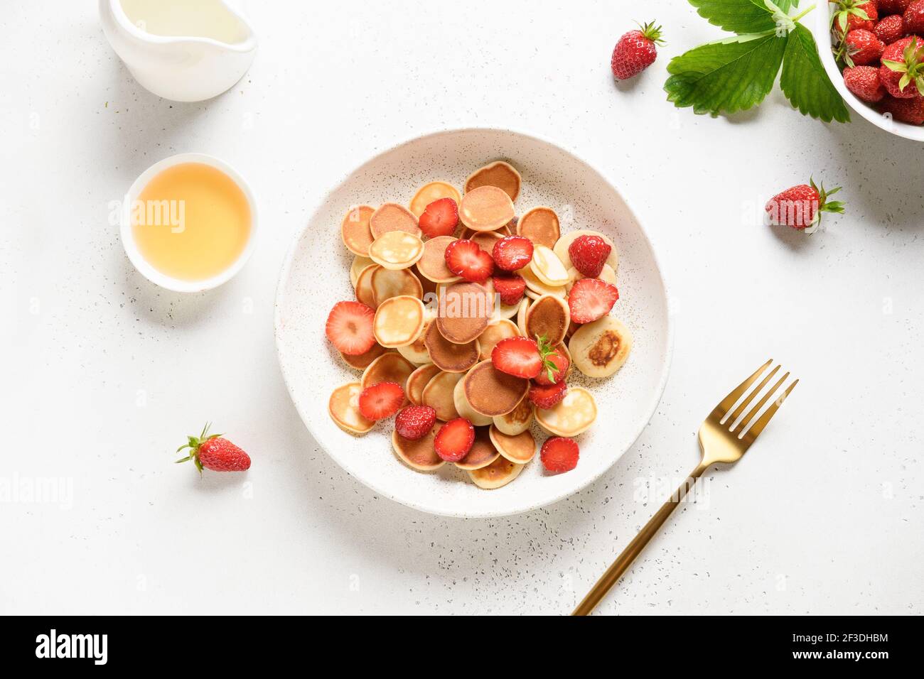 Colazione estiva con mini pancake e fragola su tavola bianca. Vista dall'alto. Foto Stock