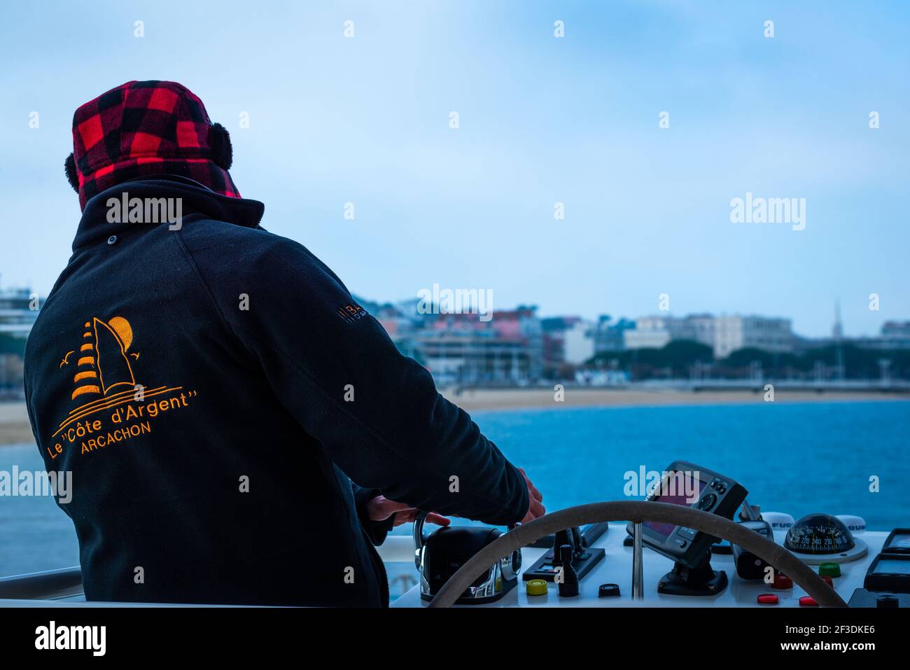 Vista posteriore della persona che guida la barca. Uomini in abiti caldi e testa coperta contro il vento freddo. Giornata invernale in mare. Foto Stock