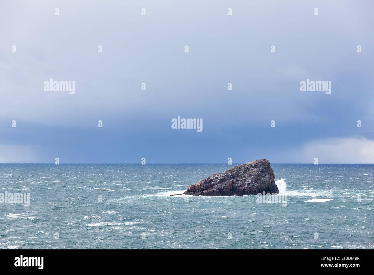 Isola rocciosa di fronte a Cap Frehel con nuvole di pioggia. Bretagna, Francia Foto Stock