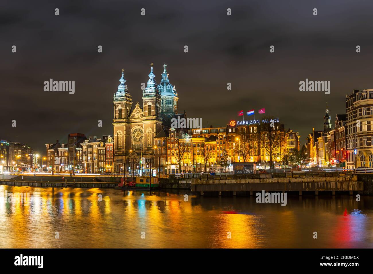 La banchina di Prins Hendrikkade e la Basilica di San Nicola ad Amsterdam di notte in Olanda, Paesi Bassi Foto Stock