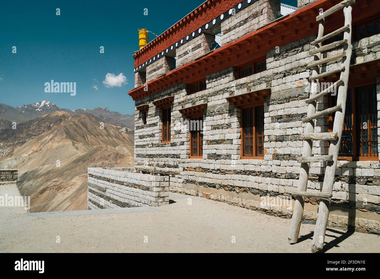 Edificio municipale costruito in pietra in tradizionali colori buddisti che si affaccia sulle cime innevate dell'Himalaya in estate a Nako, Himachal Pradesh, India. Foto Stock