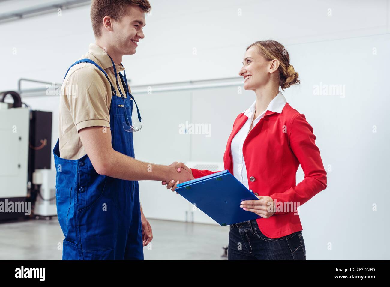 Operaio e manager che fanno stretta di mano sul pavimento della fabbrica Foto Stock