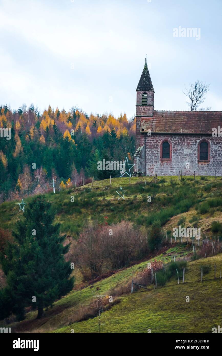 Vecchia chiesa francese a una torre sulla collina vista laterale in prateria e foresta in mosella Foto Stock