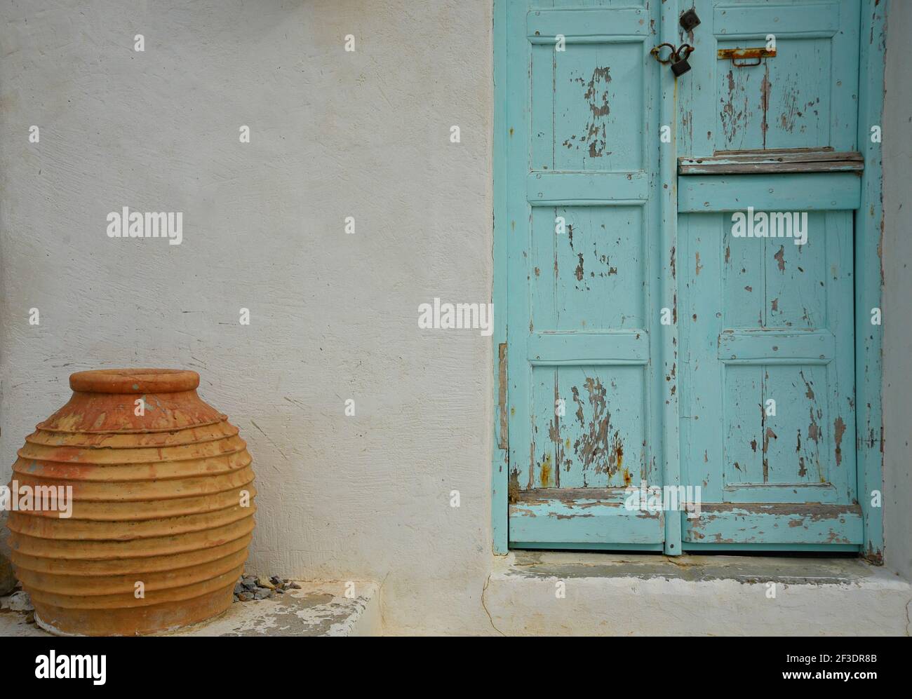 Tradizionale vecchia casa rurale facciata con una porta in legno turchese e intemperie e un'urna di terracotta nell'isola di Amorgos, Cicladi Grecia. Foto Stock