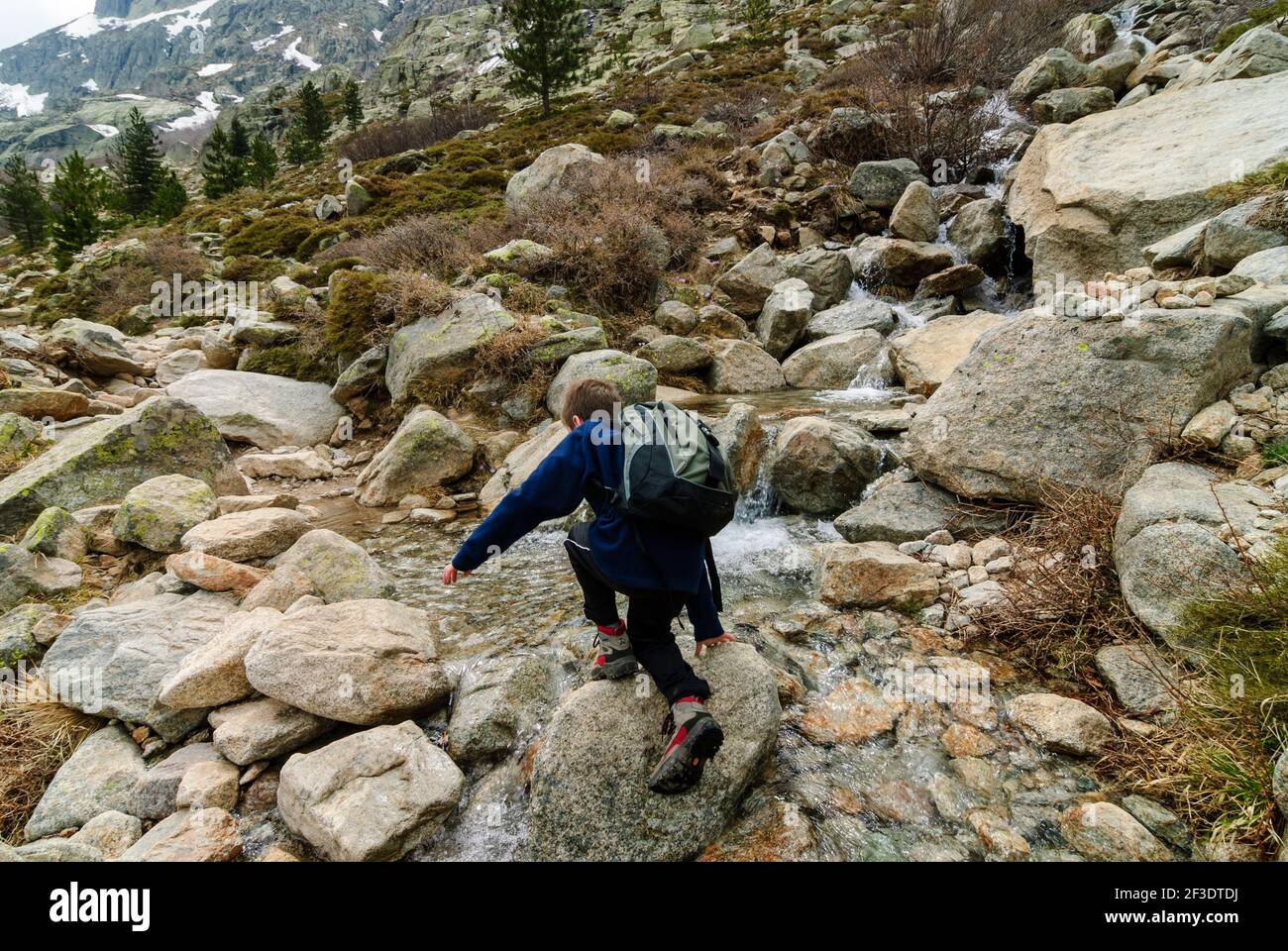 Giovane ragazzo trekking e arrampicata su sentiero roccioso in montagna della Valle Restonica in primavera, Corsica Foto Stock