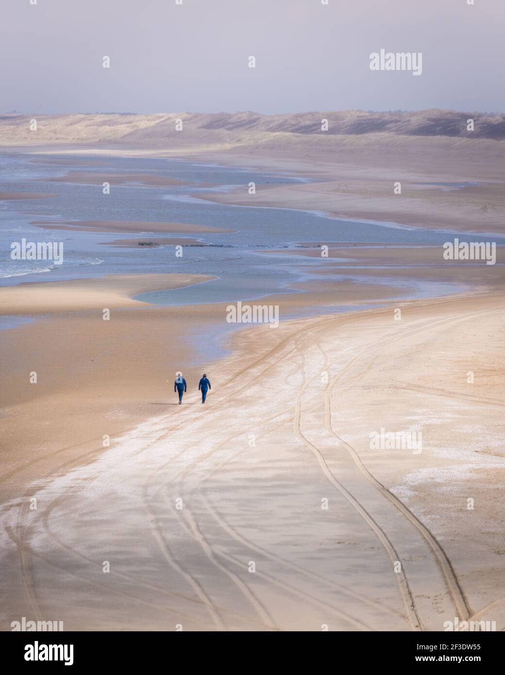 Vista aerea su due persone che camminano sulla costa del mare. Persone non identificabili sulla spiaggia di sabbia in bassa stagione. Foto Stock