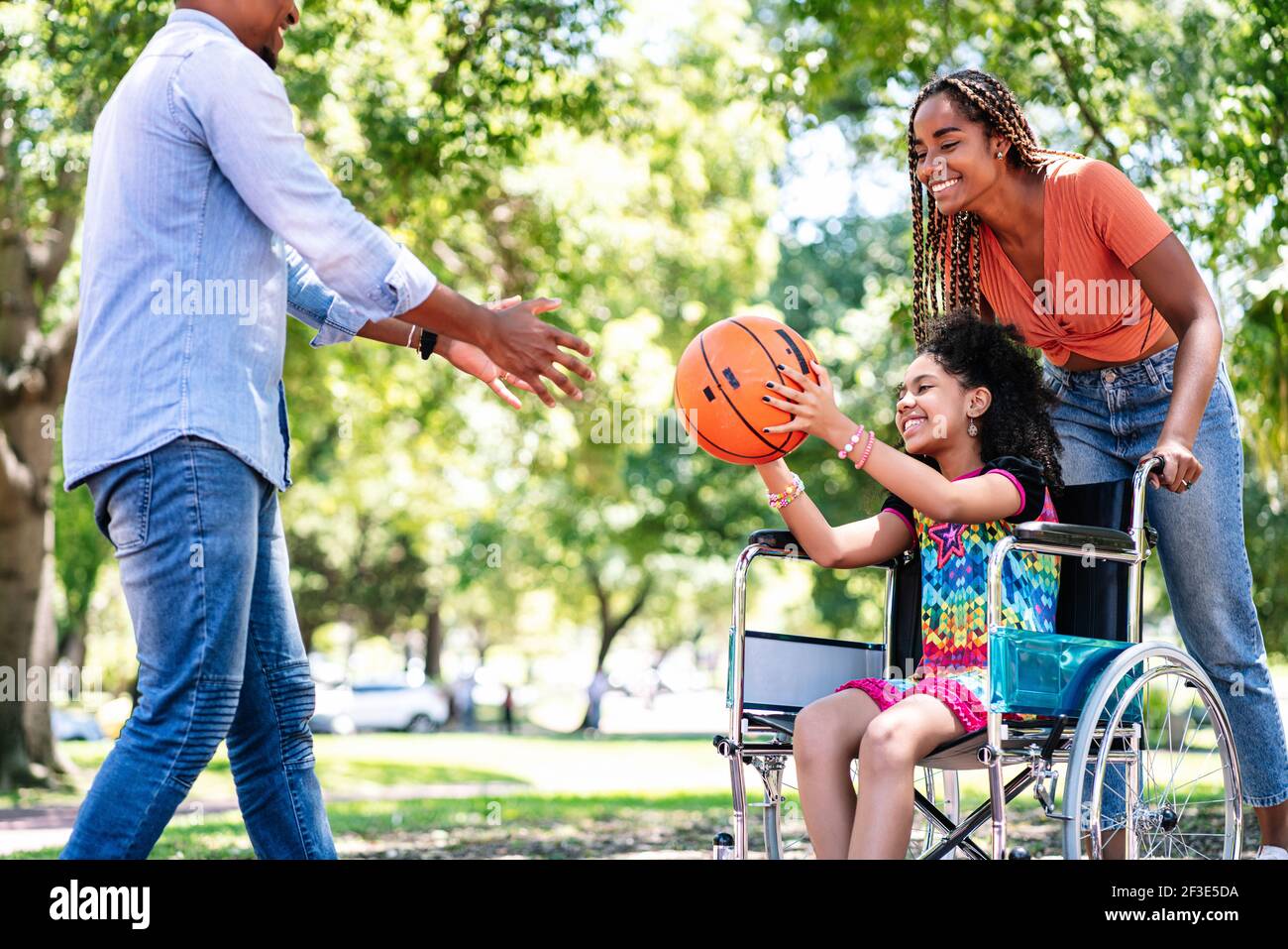 Ragazza in sedia a rotelle che gioca a basket con la sua famiglia. Foto Stock