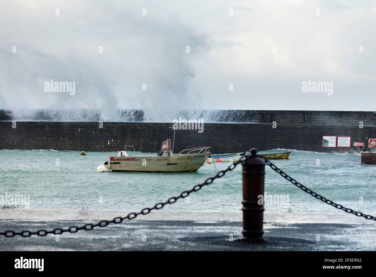 Barche oltre il muro del porto a Goury sulla penisola del Cotentin in una giornata tempesta con grandi onde, Normandia, Francia Foto Stock