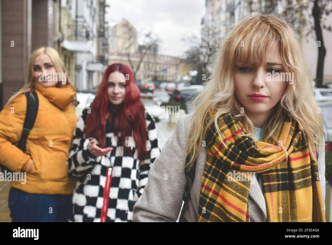 una giovane studentessa depressa con capelli biondi che è bullizzata dai suoi coetanei adolescenti, disturbata da sentimenti di disperazione e sofferenza da oppressione. s Foto Stock