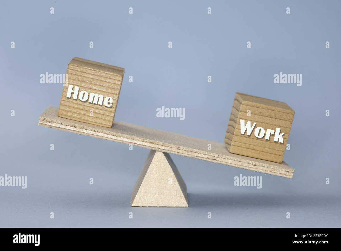 la scala di legno con blocchi che mostrano l'equilibrio rotto tra "Home" e "Work" (lavoro) con il blocco di lavoro più pesante su sfondo blu Foto Stock