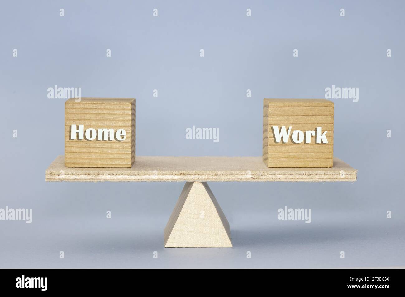 La scala di legno che mostra l'equilibrio con blocchi di legno 'Home' E 'lavoro' su sfondo blu Foto Stock