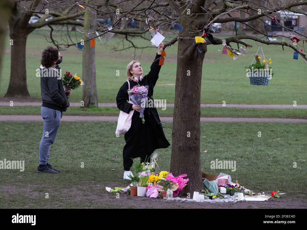 Londra, Regno Unito. 16 Marzo 2021. La gente legge tributi a Sarah Everard legato ai rami di un albero su Clapham Common. La gente continua a lasciare tributi e fiori per Sarah Everard al chiosco sul Clapham Common che è diventato un santuario. Sarah è stato visto l'ultima volta il 3 marzo. Il suo corpo è stato trovato in un sacchetto del costruttore in Woodland ad Ashord. PC Wayne Couzens è apparso al vecchio Bailey via video dal carcere di Belmarsh oggi. Sarà in prova a ottobre. Credit: Mark Thomas/Alamy Live News Foto Stock