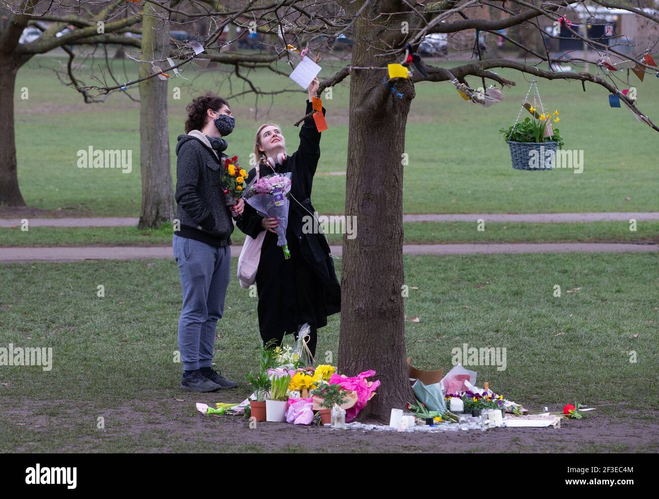 Londra, Regno Unito. 16 Marzo 2021. La gente legge tributi a Sarah Everard legato ai rami di un albero su Clapham Common. La gente continua a lasciare tributi e fiori per Sarah Everard al chiosco sul Clapham Common che è diventato un santuario. Sarah è stato visto l'ultima volta il 3 marzo. Il suo corpo è stato trovato in un sacchetto del costruttore in Woodland ad Ashord. PC Wayne Couzens è apparso al vecchio Bailey via video dal carcere di Belmarsh oggi. Sarà in prova a ottobre. Credit: Mark Thomas/Alamy Live News Foto Stock