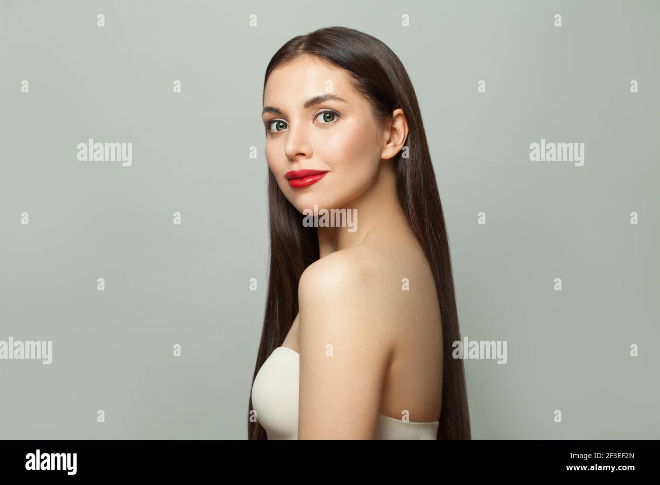 Giovane attraente modello sano Bruna donna con pelle chiara e. capelli lisci lunghi e luminosi su sfondo bianco Foto Stock
