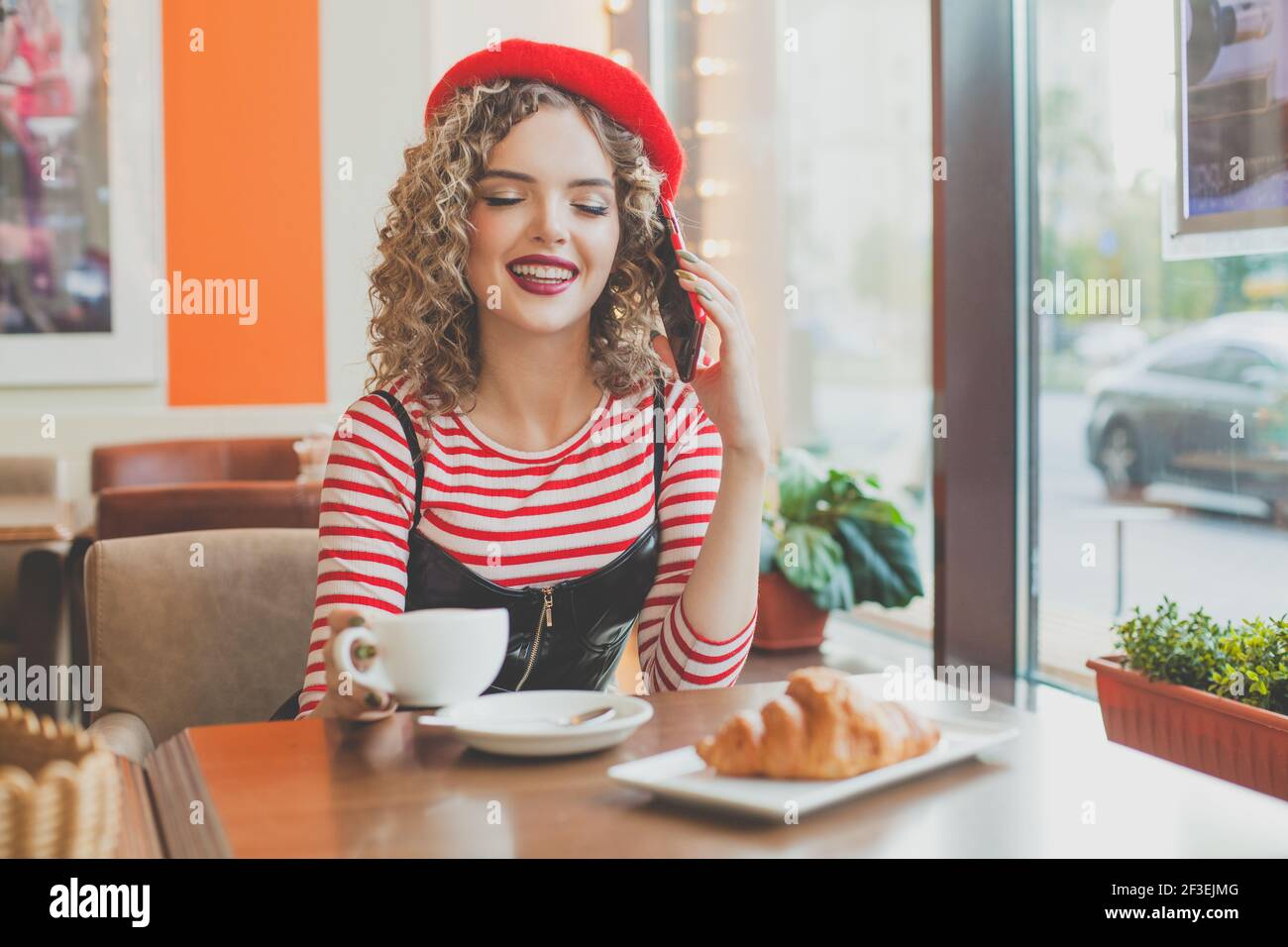 Bella giovane donna felice che chiacchiera al telefono al bar Foto Stock