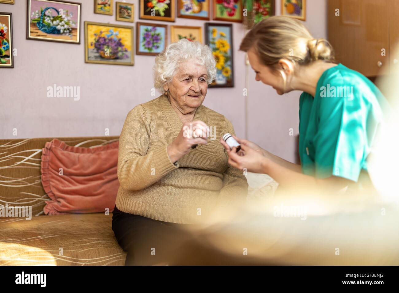 Assistente domestico che aiuta la donna anziana con il farmaco Foto Stock