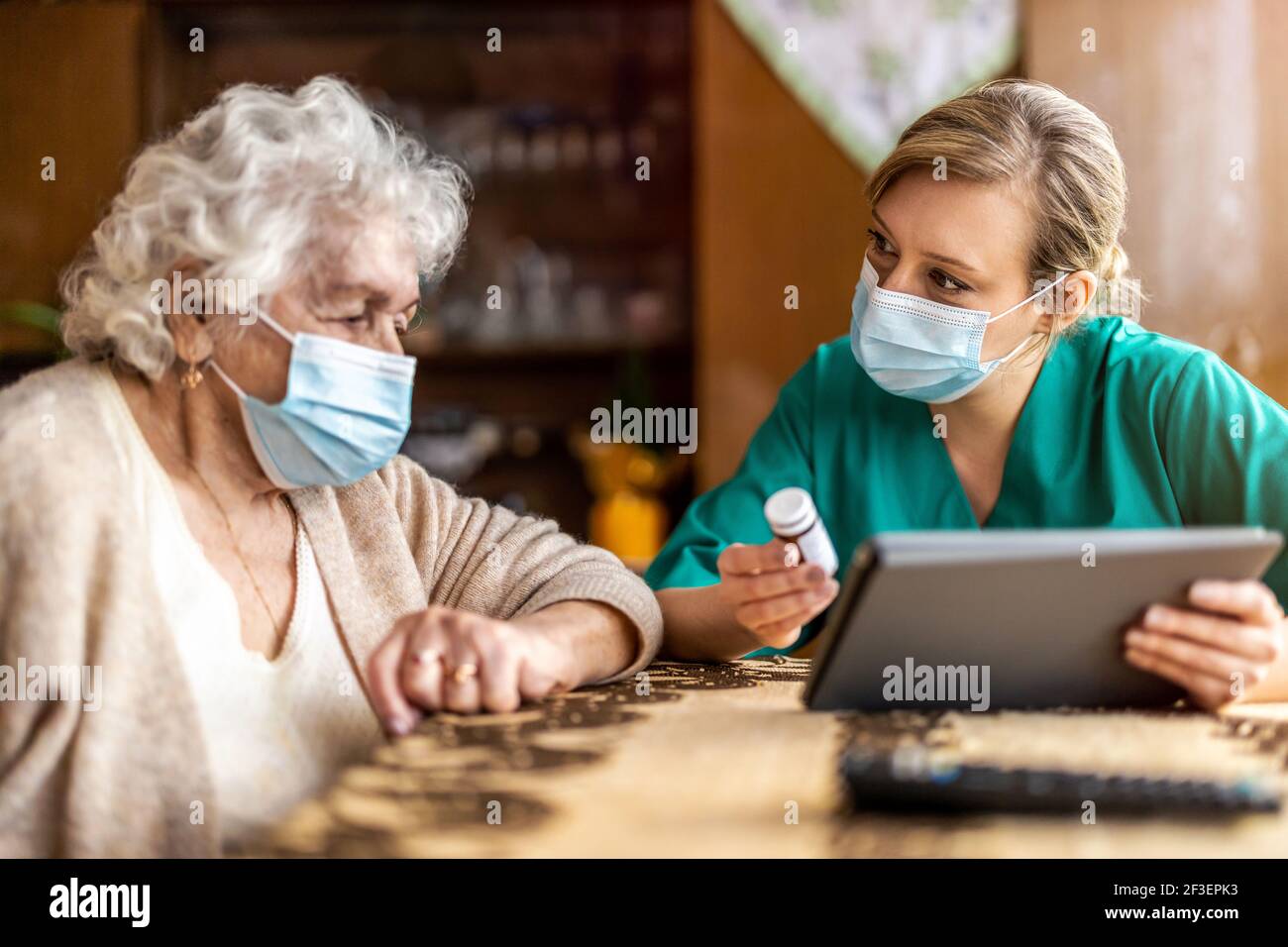 Assistente domestico che aiuta la donna anziana con il farmaco Foto Stock