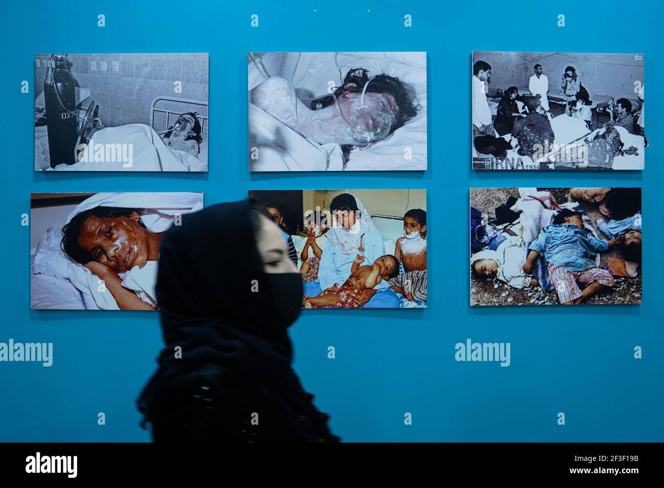 Una donna passa accanto alle foto delle vittime dell'attacco chimico di Halabja.il 33° anniversario dell'attacco chimico effettuato dal governo iracheno il 16 marzo 1988 sulla città di Halabja nella regione del Kurdistan, che ha ucciso quasi 5000 persone e ha ferito 10000 la maggior parte di loro civili. Migliaia di abitanti della città sono morti nell'anno successivo all'attacco a causa di complicazioni sanitarie e a causa di malattie e difetti congeniti. Foto Stock