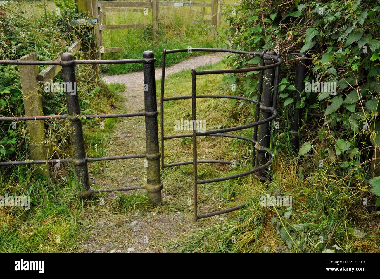 Disegno insolito vecchio ferro di getto dondolo, baciando cancello su un sentiero nel Wiltshire Foto Stock