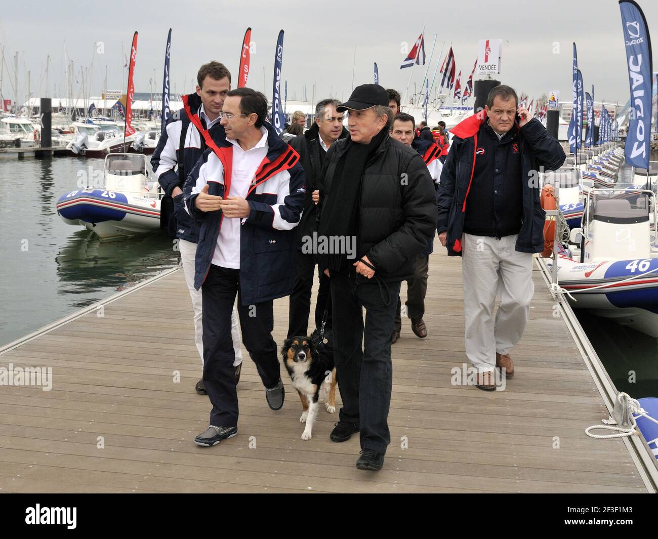 VELA - GARA MONDIALE - VENDEE GLOBE 2012/2013 - LES SABLES D'OLONNE (FRA) - 09/11/2012 - FOTO FRANCOIS VAN MALLEGHEM / DPPI - MICHEL DRUCKER / FRANCIA 2 TV CON IL SUO CANE IZIA E BRUNO RETAILLEAU / PRESIDENTE SAEM VENDEE Foto Stock