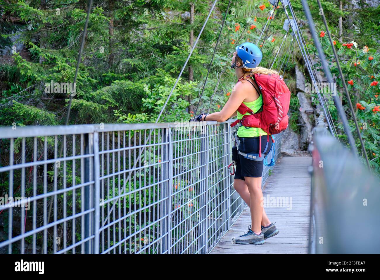 Donna con zaino e ferrata via guarda su un ponte in acciaio a Lehner Wasserfall via ferrata in Tirolo, Austria. Attività estiva, avventuroso Foto Stock