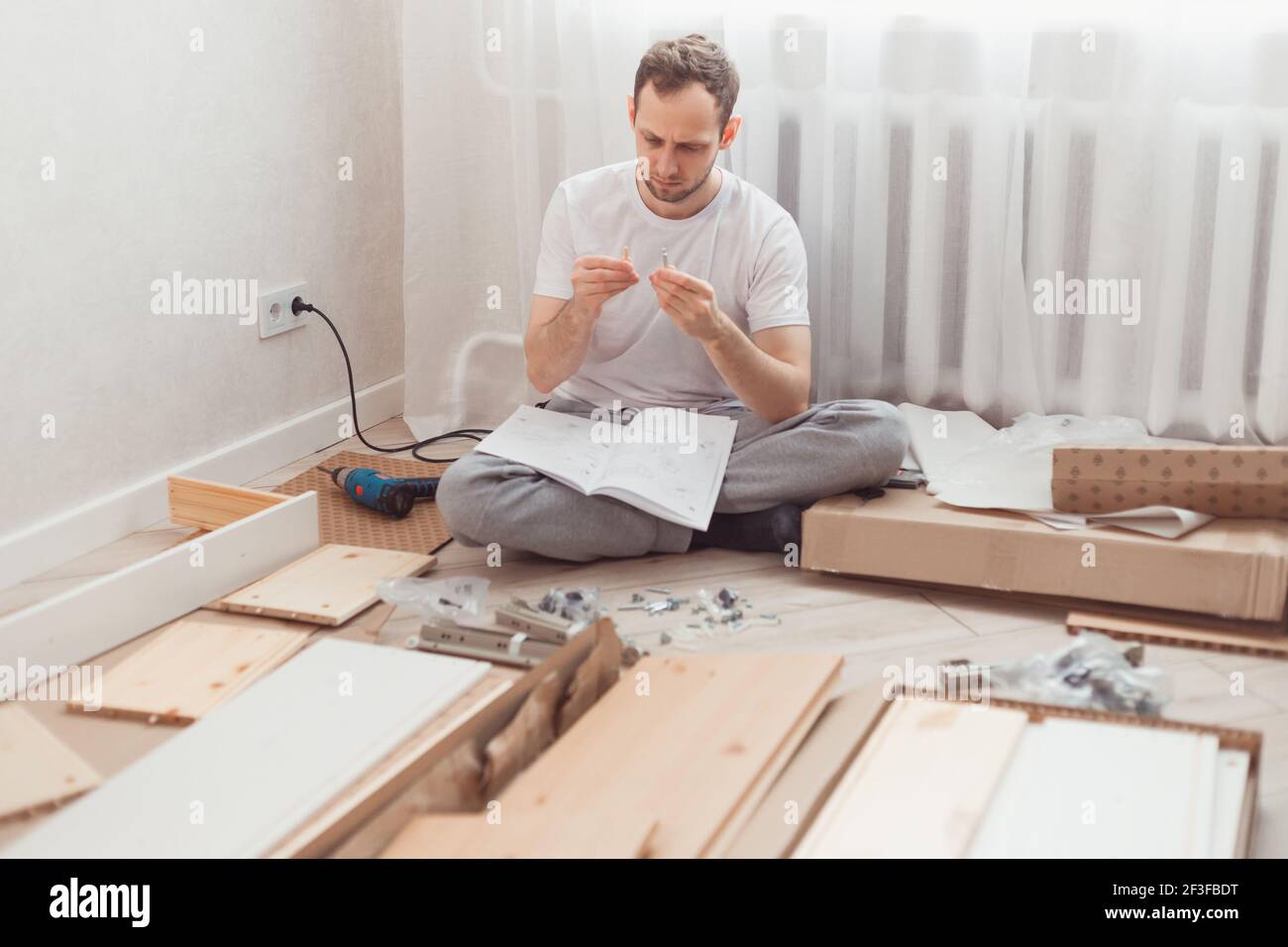 Uomo auto-assemblaggi mobili in legno a casa senza padrone. Leggere le istruzioni. Concetto DIY Foto Stock