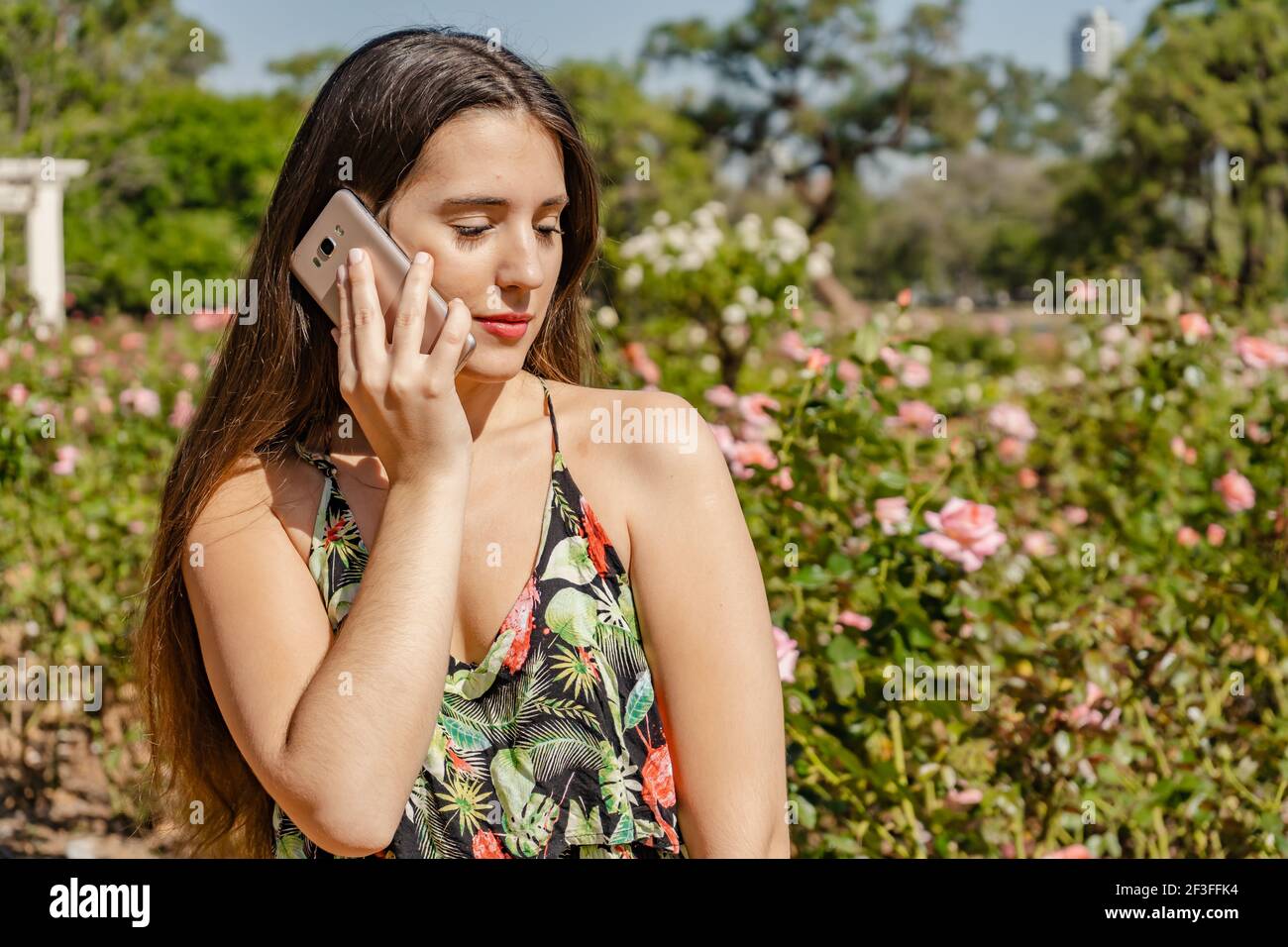 Bella giovane donna latina in un parco che parla sul suo cellulare. Concetto di comunicazione. Foto Stock