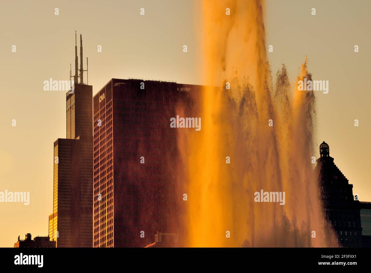 Chicago, Illinois, Stati Uniti. Il sole tramontante splende attraverso il pennacchio superiore della Buckingham Fountain di Chicago. Foto Stock