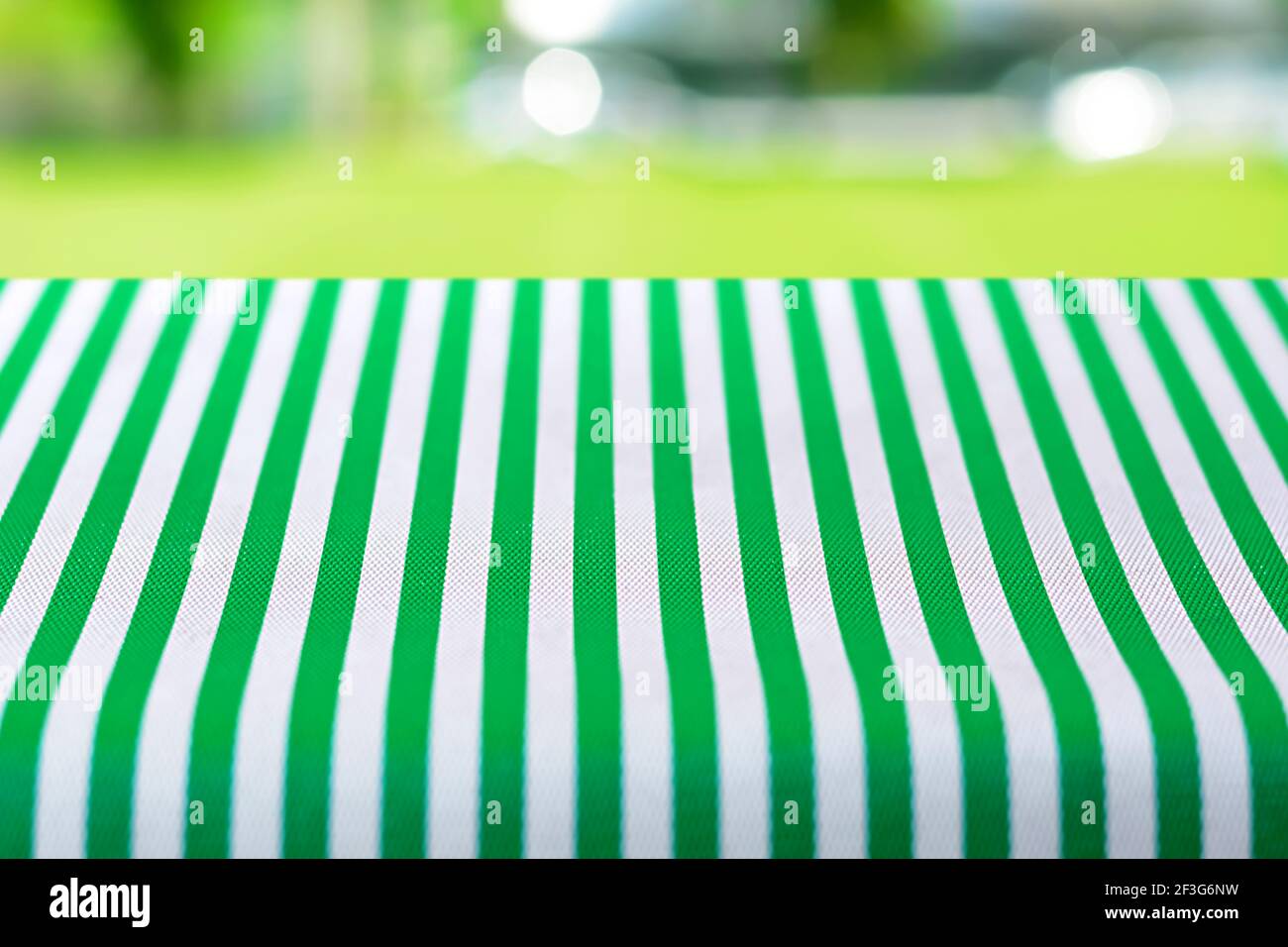 Tavolo coperto con tovaglia a righe su cortile verde sfocato sfondo - può essere utilizzato per il montaggio o la visualizzazione del prodotti Foto Stock