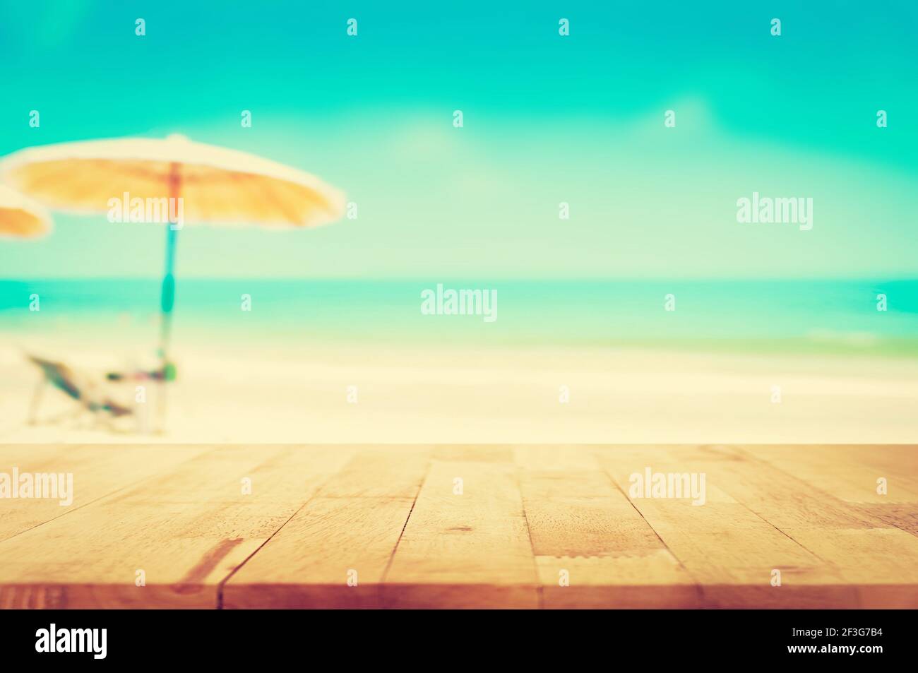 Tavolo in legno su mare blu sfocato e sabbia bianca sfondo spiaggia, tonalità vintage - può essere utilizzato per la visualizzazione o montaggio dei vostri prodotti Foto Stock