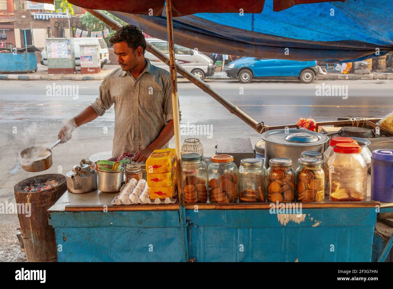 Uomo che prepara il tè al locale stallone stradale a Kolkata, India Foto Stock