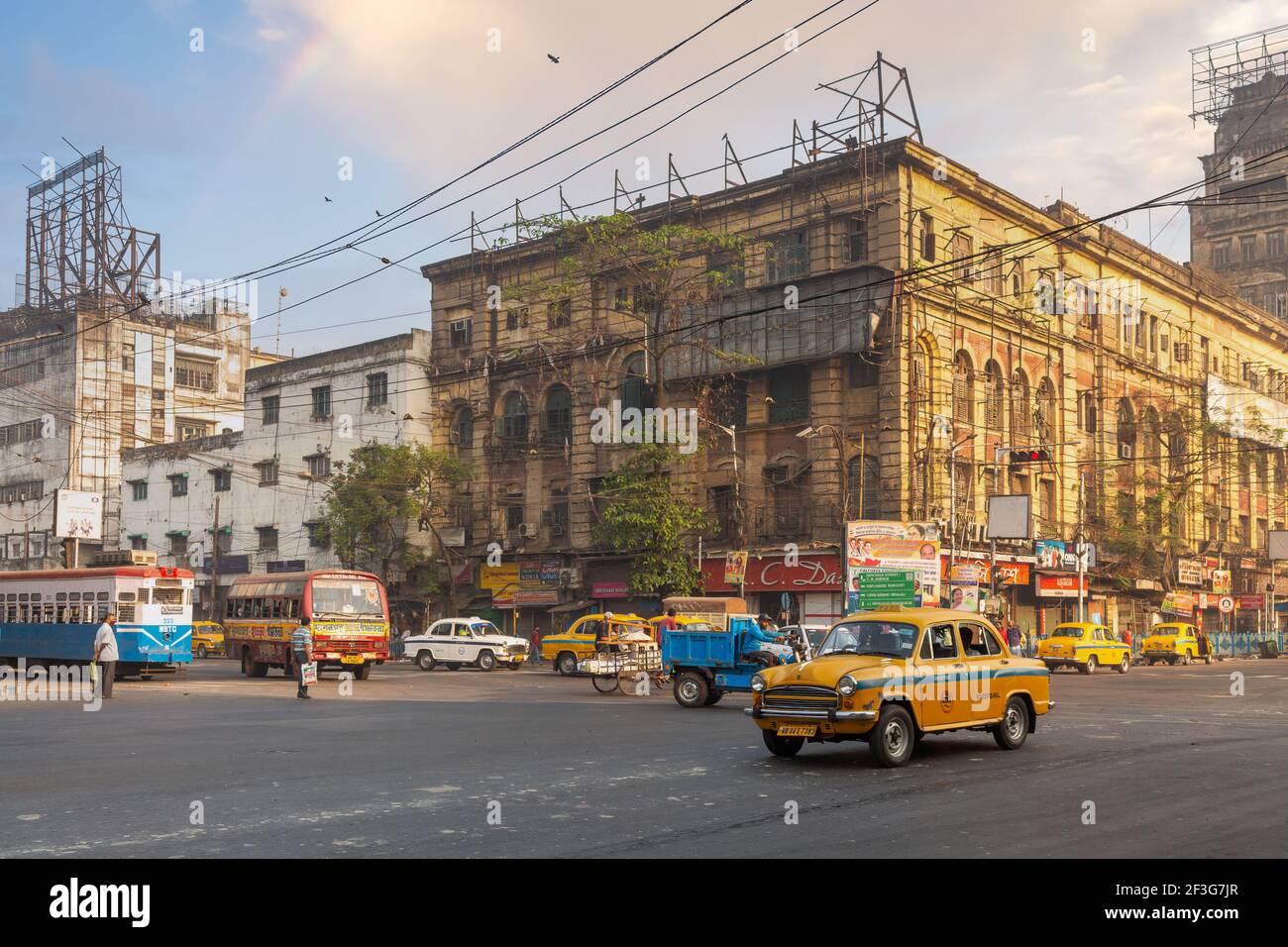 Taxi giallo e autobus di trasporto pubblico sulla strada della città con vecchi edifici di uffici nella zona Esplanade di Kolkata, India Foto Stock