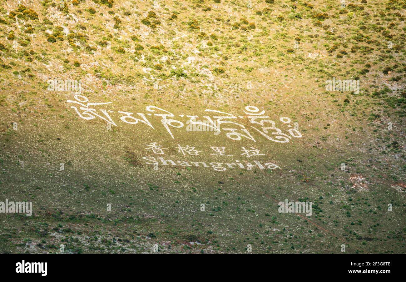 Cartello della città di Shangri-la con il nome scritto sulla montagna in inglese Caratteri cinesi e alfabeto tibetano in Cina Shangri-la Yunnan Foto Stock