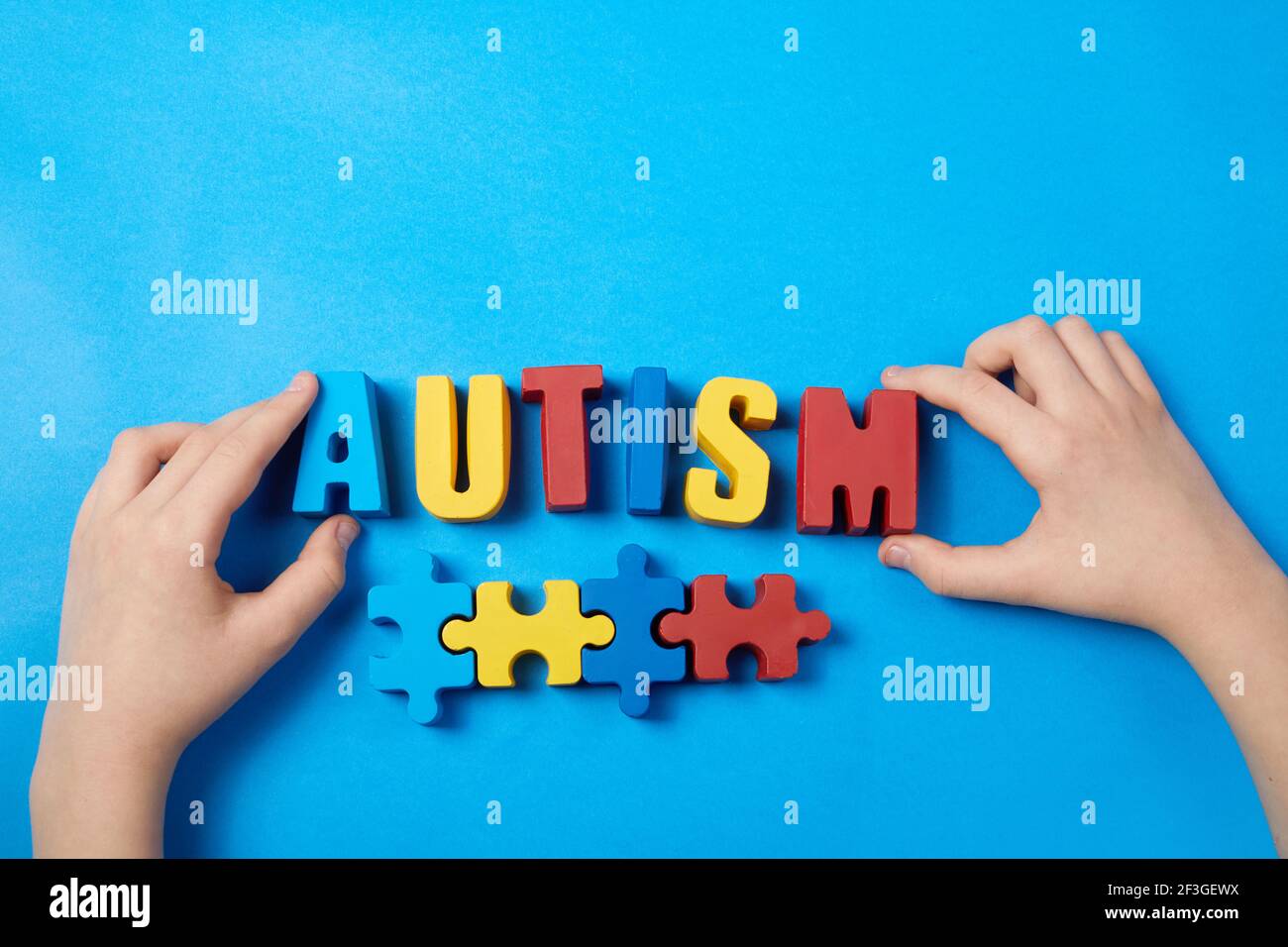 Autistico capretto mani che tengono puzzle puzzle e autismo parola, concetto di salute mentale. Spettro autismo, disturbo. Giornata mondiale di consapevolezza dell'autismo. Foto Stock