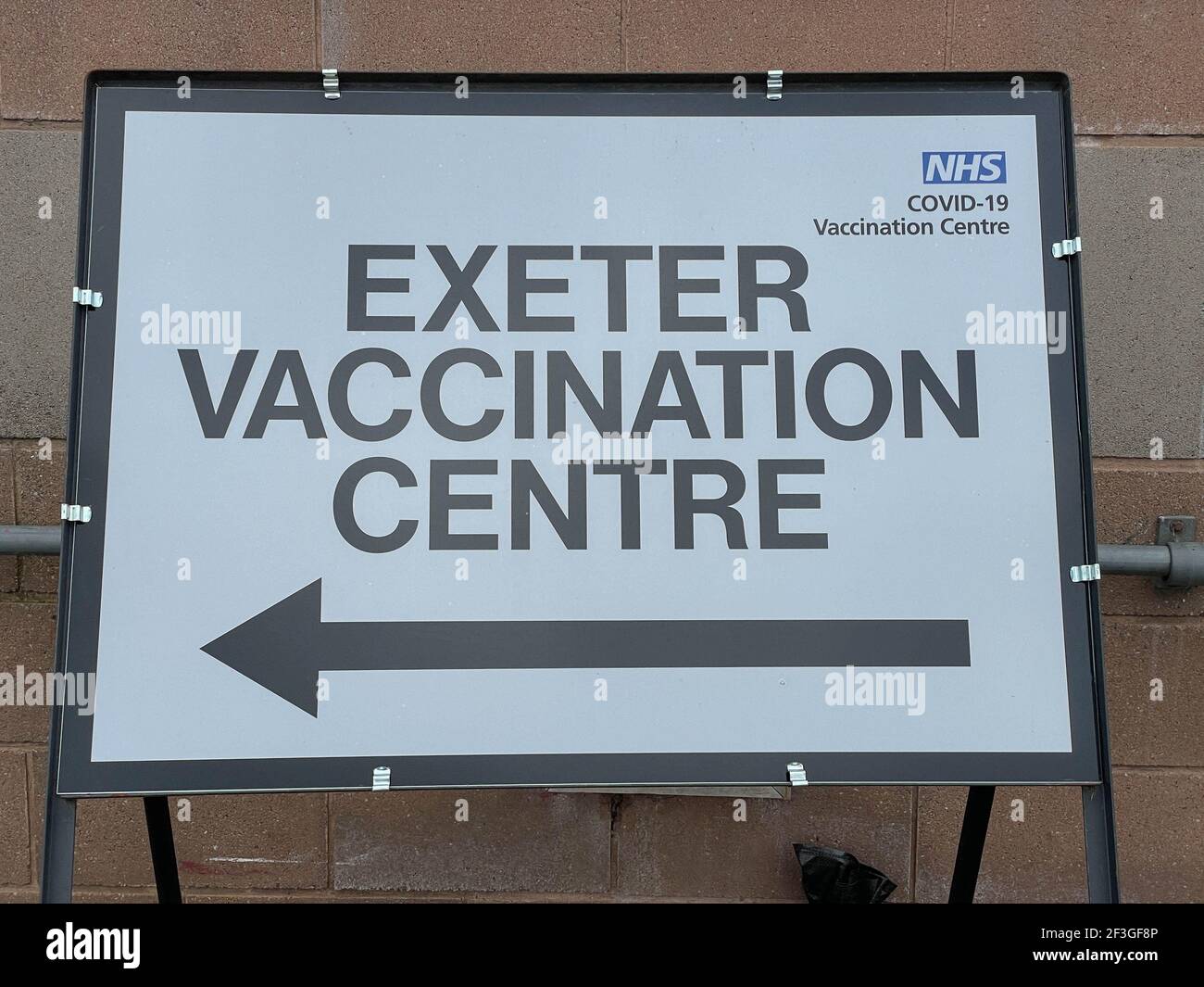 Free Standing Metal Sign con una freccia che punta verso il NHS Covid-19 Exeter Vaccination Center, Devon, Inghilterra, Regno Unito Foto Stock