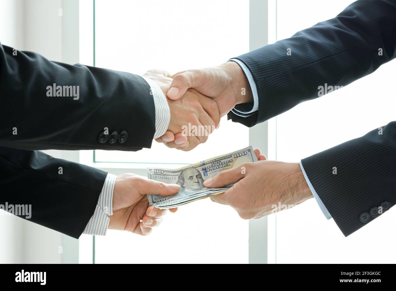 Uomini d'affari che fanno stretta di mano mentre passano i soldi - affare & corruzione concetti Foto Stock