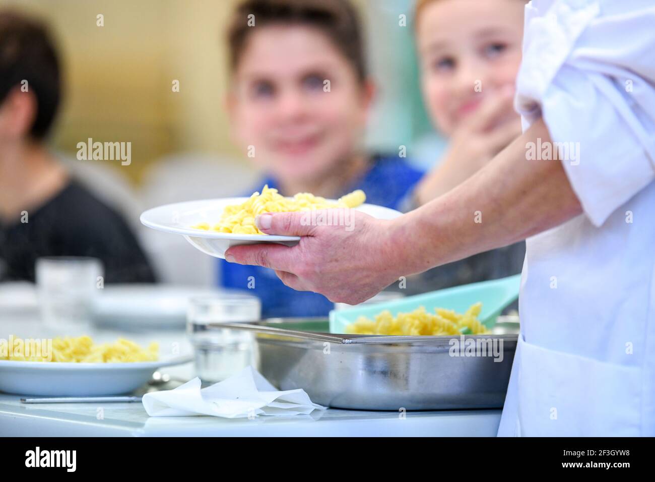 Dipendente che serve pasti nella mensa scolastica di una scuola primaria durante il secondo periodo di blocco a causa dell'epidemia di COVID-19, il 2 novembre 2020 Foto Stock
