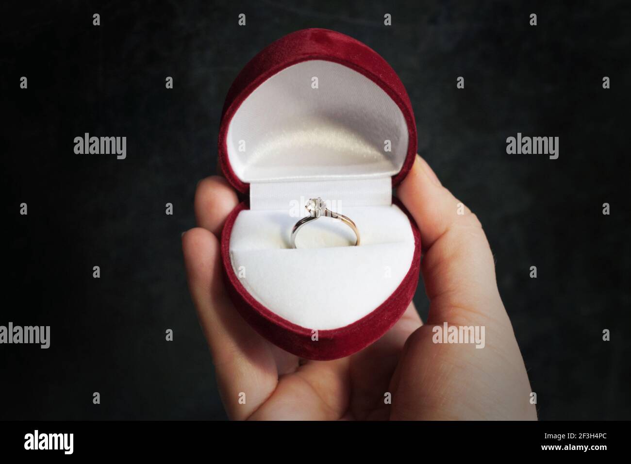 Anello di nozze regalo in una custodia sotto forma di un cuore in mano. Foto Stock