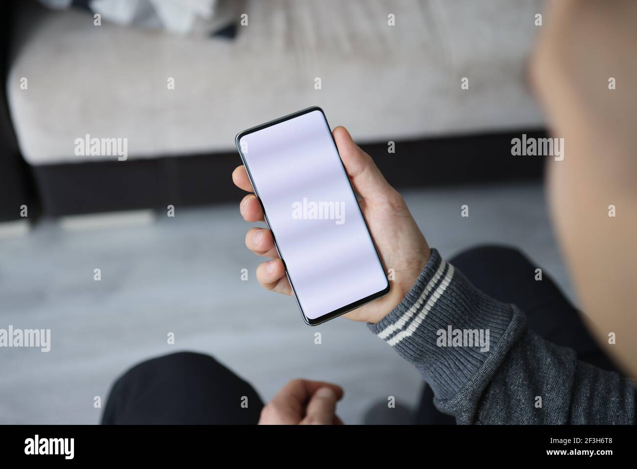 L'uomo tiene lo smartphone con lo schermo bianco in mano Foto Stock