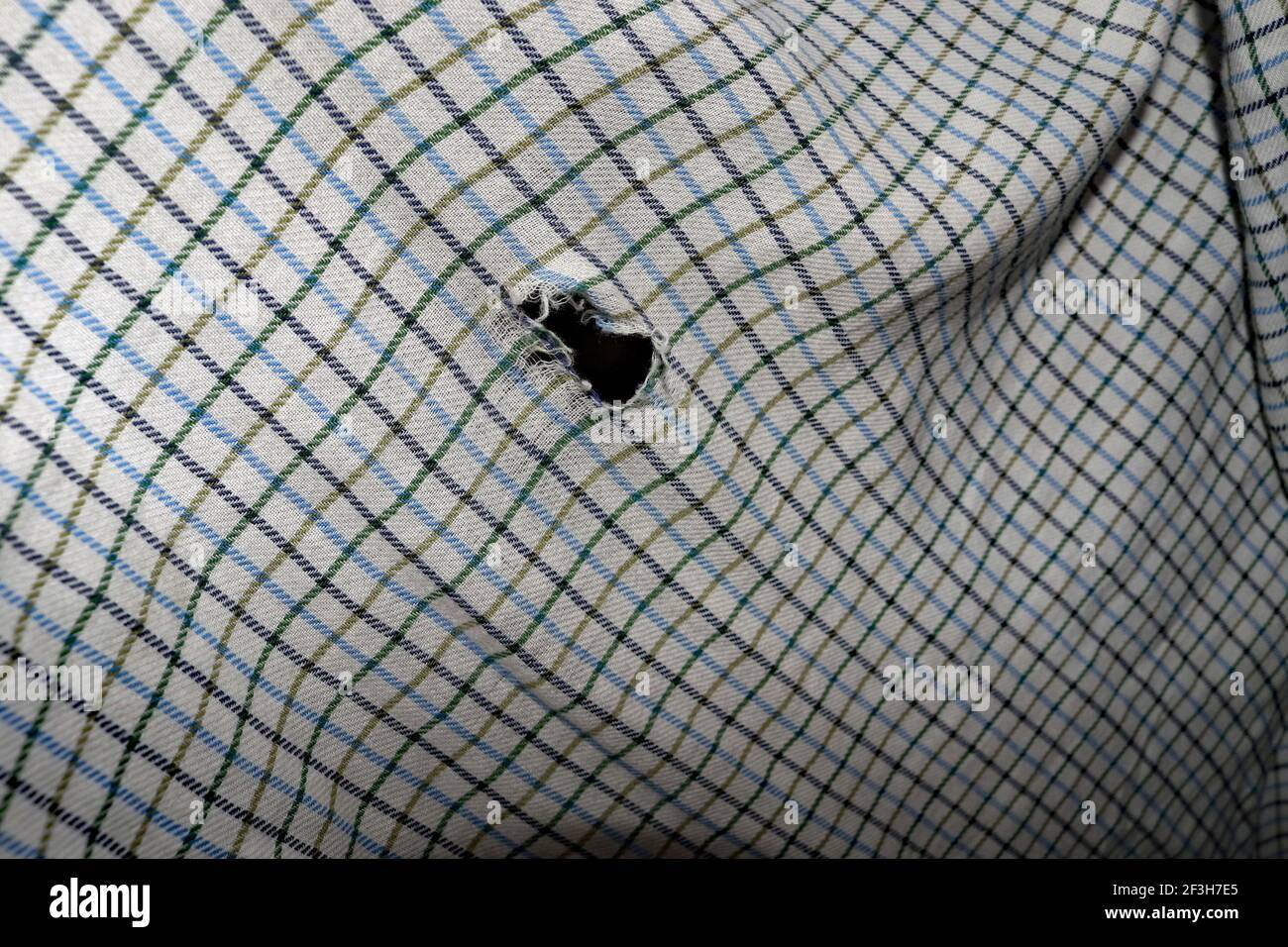 Una vecchia camicia molto amata è giunta alla fine della sua vita utile che si indossa e ci sono buchi nel materiale del retro della camicia. Foto Stock