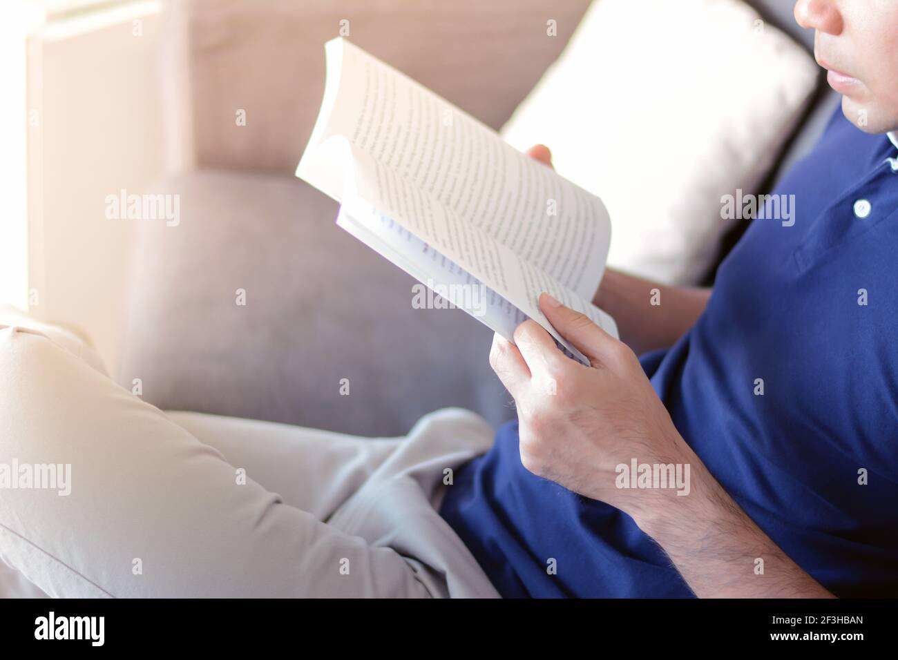 Un uomo che legge libro mentre si sdraiò sul divano Foto Stock