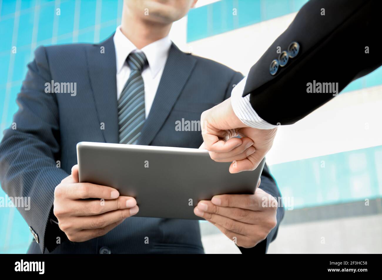 Due uomini d'affari che guardano un tablet pc con una mano che punta allo schermo - concetto di discussione aziendale Foto Stock